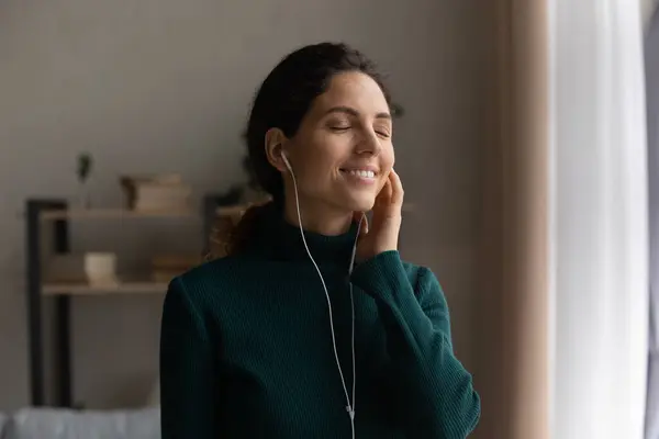 Happy inspired young woman listening music in wired earphones. — Stock Photo, Image