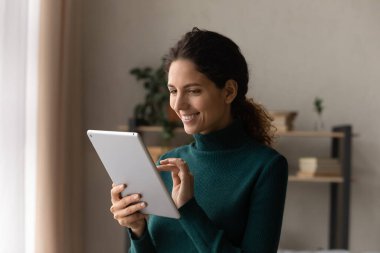 Happy young hispanic woman using tablet at home.