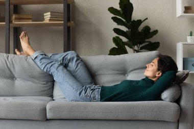 Happy peaceful hispanic woman relaxing on comfortable couch.