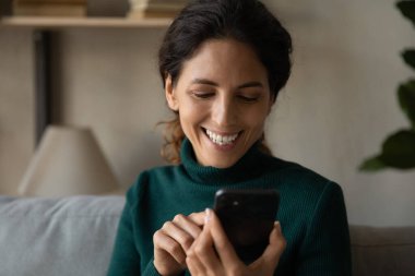 Happy young attractive woman using cellphone at home.
