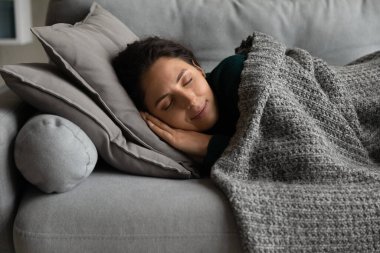 Relaxed peaceful young woman sleeping on sofa at home.