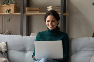 Happy young female freelancer working on computer at home.