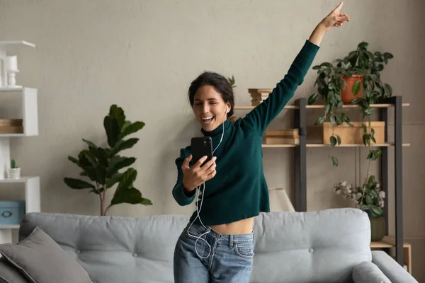 Overjoyed millennial woman dancing, holding smartphone in hands. — Stockfoto