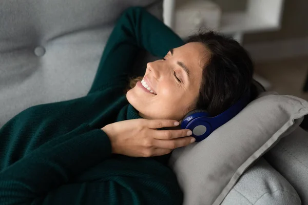 Smiling pretty hispanic woman listening music in headphones. — Stockfoto