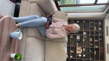 Older woman sit on couch use digital tablet