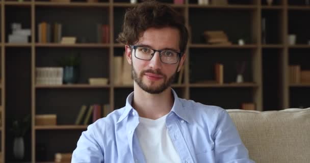 Cabeza retrato millennial chico en gafas sonrisa mira a la cámara — Vídeo de stock