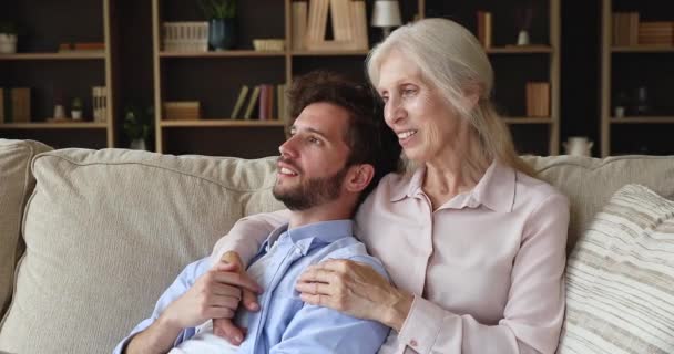 Dreamy adult son his older mom daydreaming relax on sofa — Vídeo de Stock