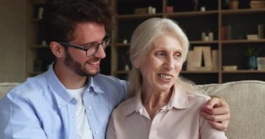 Loving adult son hugs older mom enjoy conversation at home