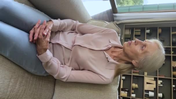 Sad pensive older woman sit on sofa thinking about life — ストック動画