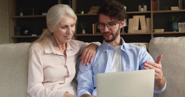 Older woman her grownup son use laptop websurfing media news — Stock video