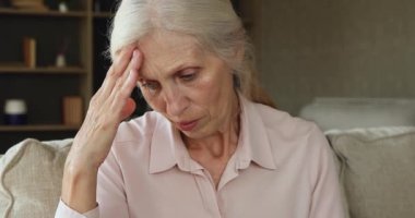 Sad yearning mature woman sit on sofa deep in thoughts