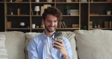 Guy sit on sofa looks at cellphone screen read news
