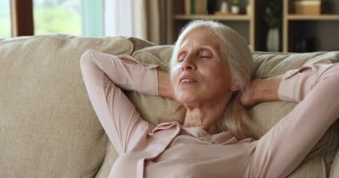 Closeup peaceful older woman enjoy day rest lying on couch