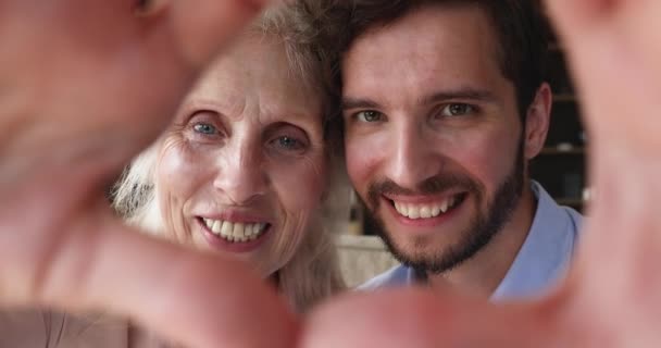 Mujer mayor, hijo adulto se enfrenta a través de dedos unidos mostrando amor — Vídeo de stock