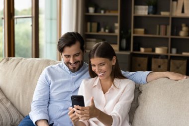 Couple looking at cellphone screen enjoy conversation using video call
