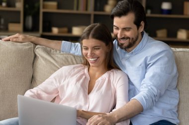 Beautiful couple relaxing on couch in living room with laptop