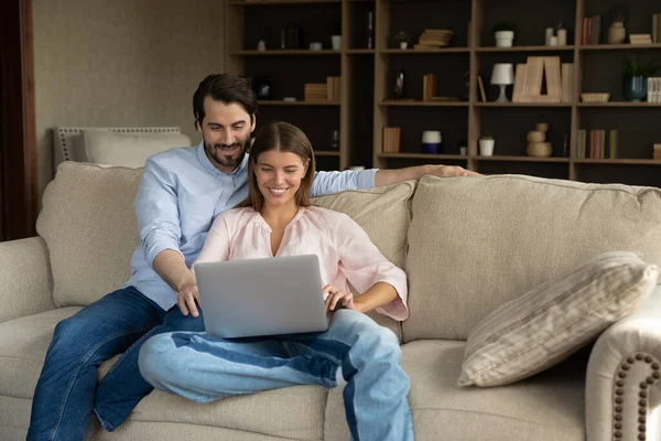 Pareja casada sentarse en un acogedor sofá con ordenador portátil —  Fotos de Stock