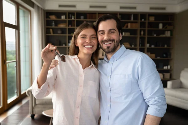 Propietarios pareja sosteniendo llaves manojo sintiéndose feliz en día de reubicación — Foto de Stock
