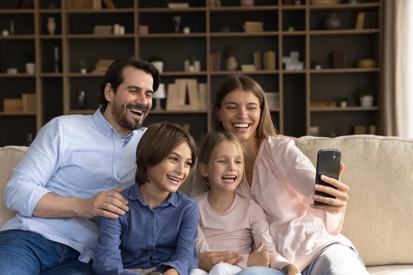 Couple and children looking at cellphone screen making selfie — стоковое фото