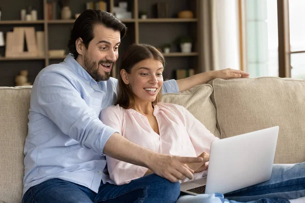 Couple looking at laptop screen read great news feels amazed — стоковое фото