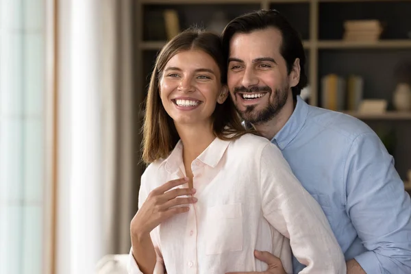 Beautiful couple standing in living room smiling looking into distance — Φωτογραφία Αρχείου