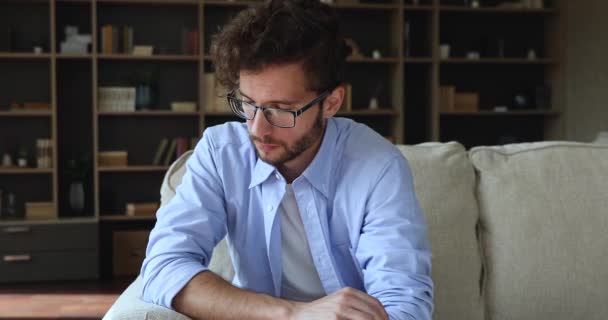 Upset guy sit on sofa deep in sad thoughts — Stockvideo