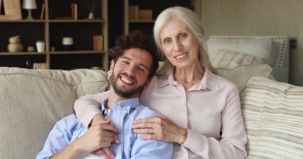 Older mum adult son relax on sofa look at camera — стоковое видео