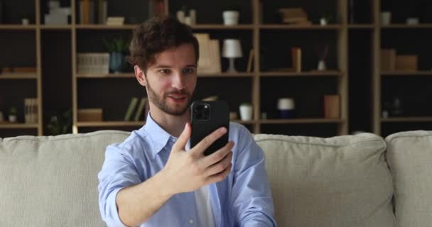 Hombre sosteniendo el teléfono celular hace llamadas de videoconferencia habla con un amigo — Vídeo de stock