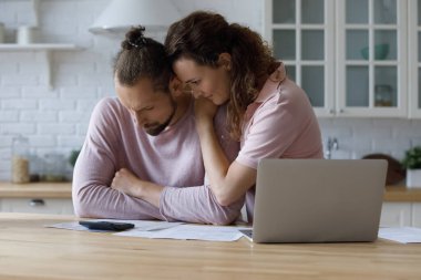 Unhappy young woman supporting stressed husband, having financial problems.