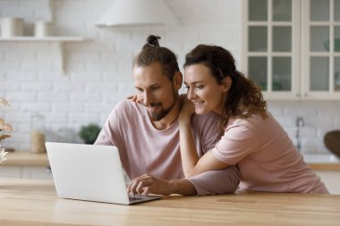 Affectionate loving millennial family couple using computer applications.