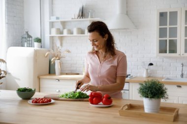 Happy millennial woman preparing healthy food in kitchen.