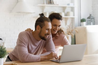 Smiling bonding young family couple using computer.