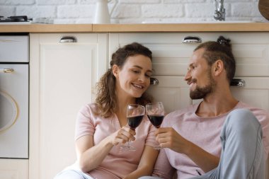 Happy affectionate young couple clinking glasses with wine.