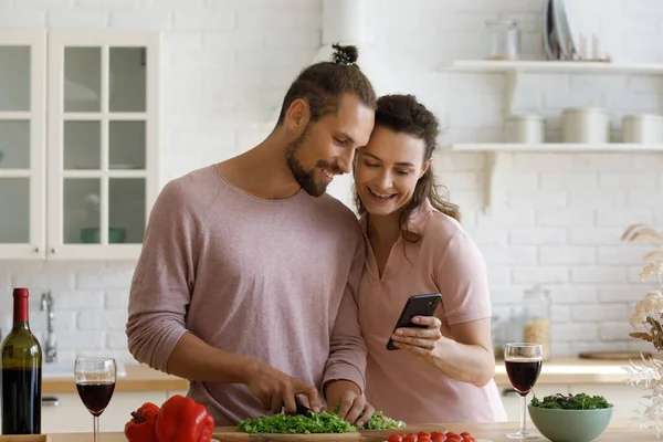 Bonding family couple cooking on weekend, using cellphone. — Stock Photo, Image