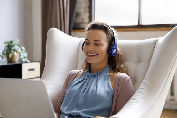 Joyful millennial woman in headphones using computer. — Stockfoto