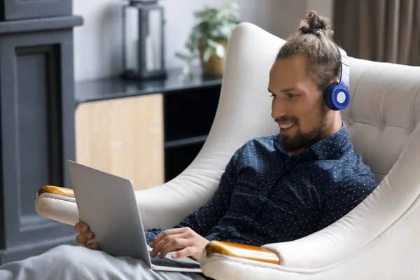 Happy relaxed young man in headphones using computer. — Stockfoto