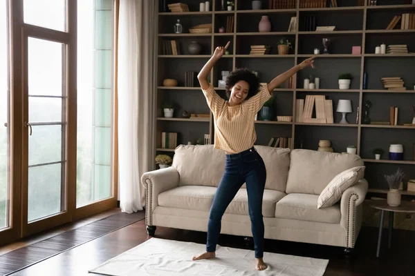 Happy carefree young African American woman dancing at home. — Zdjęcie stockowe