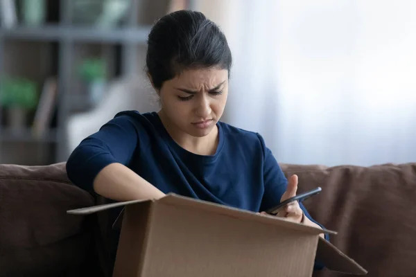 Stressed young Indian woman unpacking carton box. — Foto de Stock