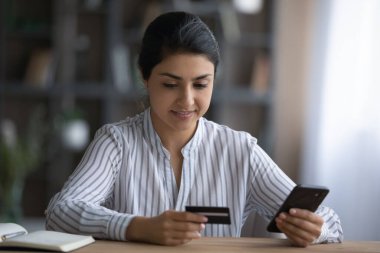 Happy young Indian woman shopping in internet store.