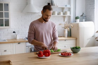 Happy young handsome man preparing healthy food in kitchen.