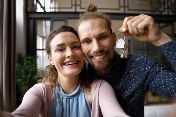 Happy loving young couple showing keys to camera. — Stock Photo, Image
