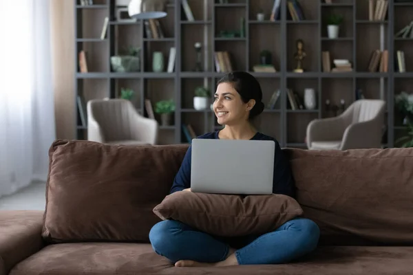 Happy dreamy young Indian woman working on computer at home. — Foto de Stock