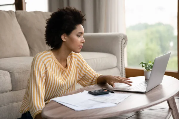 Concentrate young African American woman paying for domestic services online. — Foto de Stock