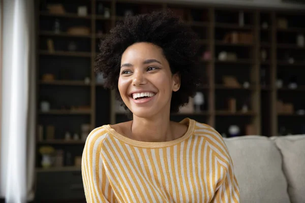 Happy dreamy young African American sincere woman looking in distance. — Stockfoto