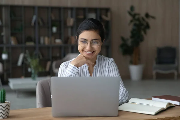 Smiling motivated Indian businesswoman in eyeglasses working on laptop. — Stock fotografie