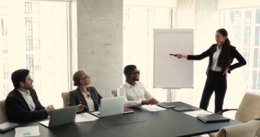 Business coach makes presentation on flip chart to multiethnic partners