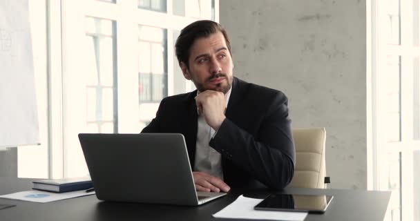 Thoughtful millennial businessman working on laptop at workplace — Stock videók