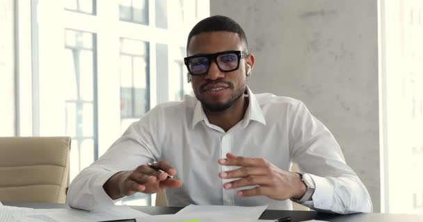 African employee wear earbuds talks on video call to client — Video