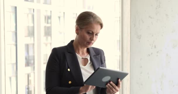 Бізнес-леді середнього віку тримає цифровий планшет думає про корпоративне завдання — стокове відео