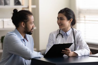 Smiling millennial Indian doctor discussing test results with patient.
